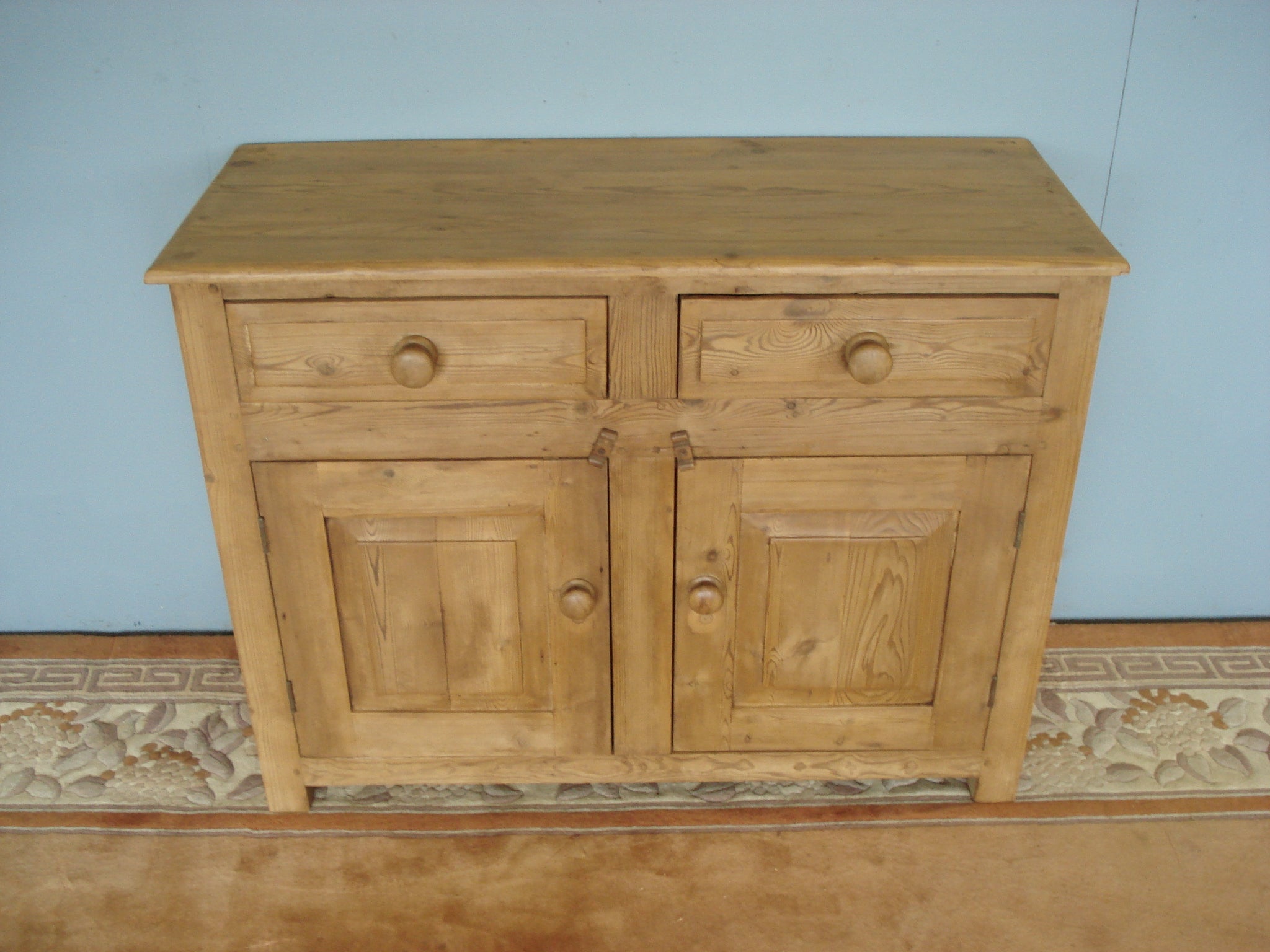 A panelled small old pine dresser base on stile supports
