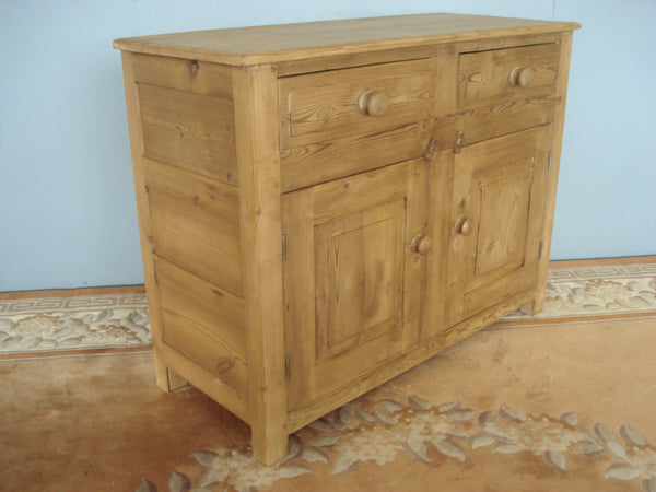 A panelled small old pine dresser base on stile supports